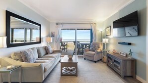 A modern living room with a sofa, armchair, coffee table, and a TV on a wooden stand. - Upgraded for 2026 Huge Deck, Full-Size Pool, Beach Front, Linens Included (Carolina Beach)
