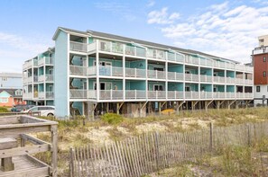A multi-story beachfront building with balconies and a wooden deck area. - Upgraded for 2026 Huge Deck, Full-Size Pool, Beach Front, Linens Included (Carolina Beach)