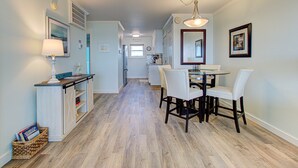 A hallway with a dining area featuring a table and chairs, a lamp, and a basket of books. - Upgraded for 2026 Huge Deck, Full-Size Pool, Beach Front, Linens Included (Carolina Beach)