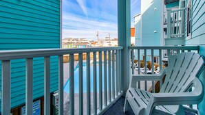 A turquoise building with a balcony, a pool, and a chair. - Upgraded for 2026 Huge Deck, Full-Size Pool, Beach Front, Linens Included (Carolina Beach)