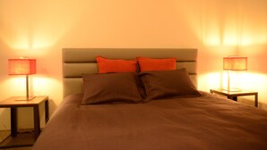 A neatly made bed with a headboard, two pillows, and two bedside tables with lamps. - Fresh New EU COMMISSION area apartment  (Bruxelles)