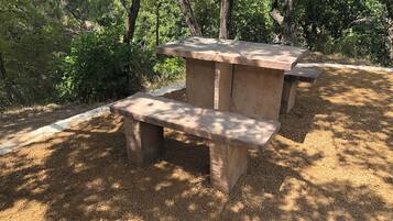 Una mesa de piedra con bancos en un área boscosa.