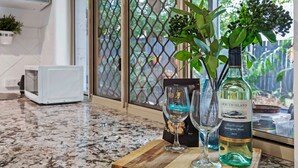 A kitchen counter with a bottle of South Island Sauvignon Blanc 2023, two wine glasses, and a potted plant. - Bulimba Central 2BR -Sleeps 6, Courtyard (Balmoral)