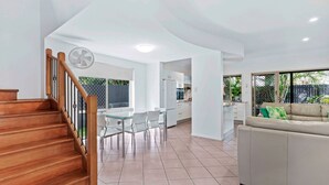 A spacious living area with a wooden staircase, a dining table with chairs, a sofa, and a kitchen in the background. - Bulimba Central 2BR -Sleeps 6, Courtyard (Balmoral)