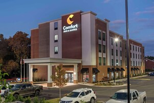 A Comfort Inn & Suites building with a prominent sign, multiple windows, and a parking lot with several vehicles.