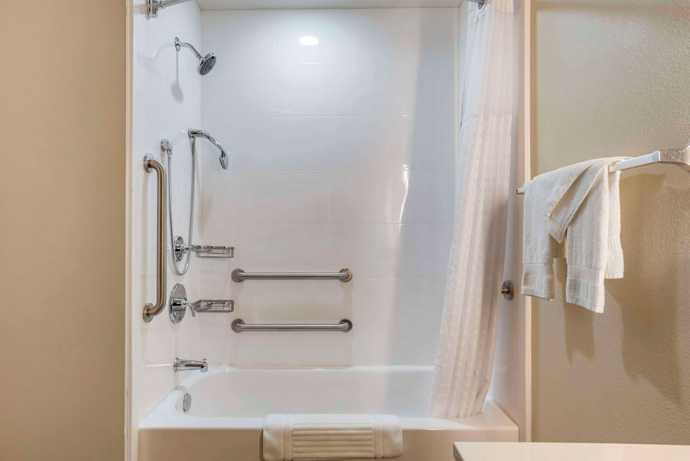 Une salle de bain équipée d’une baignoire, d’une douche et de barres d’appui.