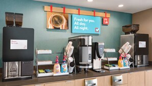 A coffee station with multiple coffee machines, a sign indicating fresh coffee availability, and dispensers for coffee creamer and milk. - avid hotel Prattville - Montgomery North by IHG (Prattville)