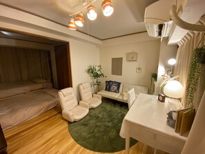 A cozy room with a bed, two chairs, a sofa, a small table, and a green rug.
