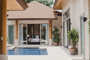 A modern house with a swimming pool, sliding glass doors, and potted plants.