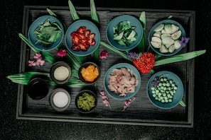 A tray with various food items and leaves on a dark surface.