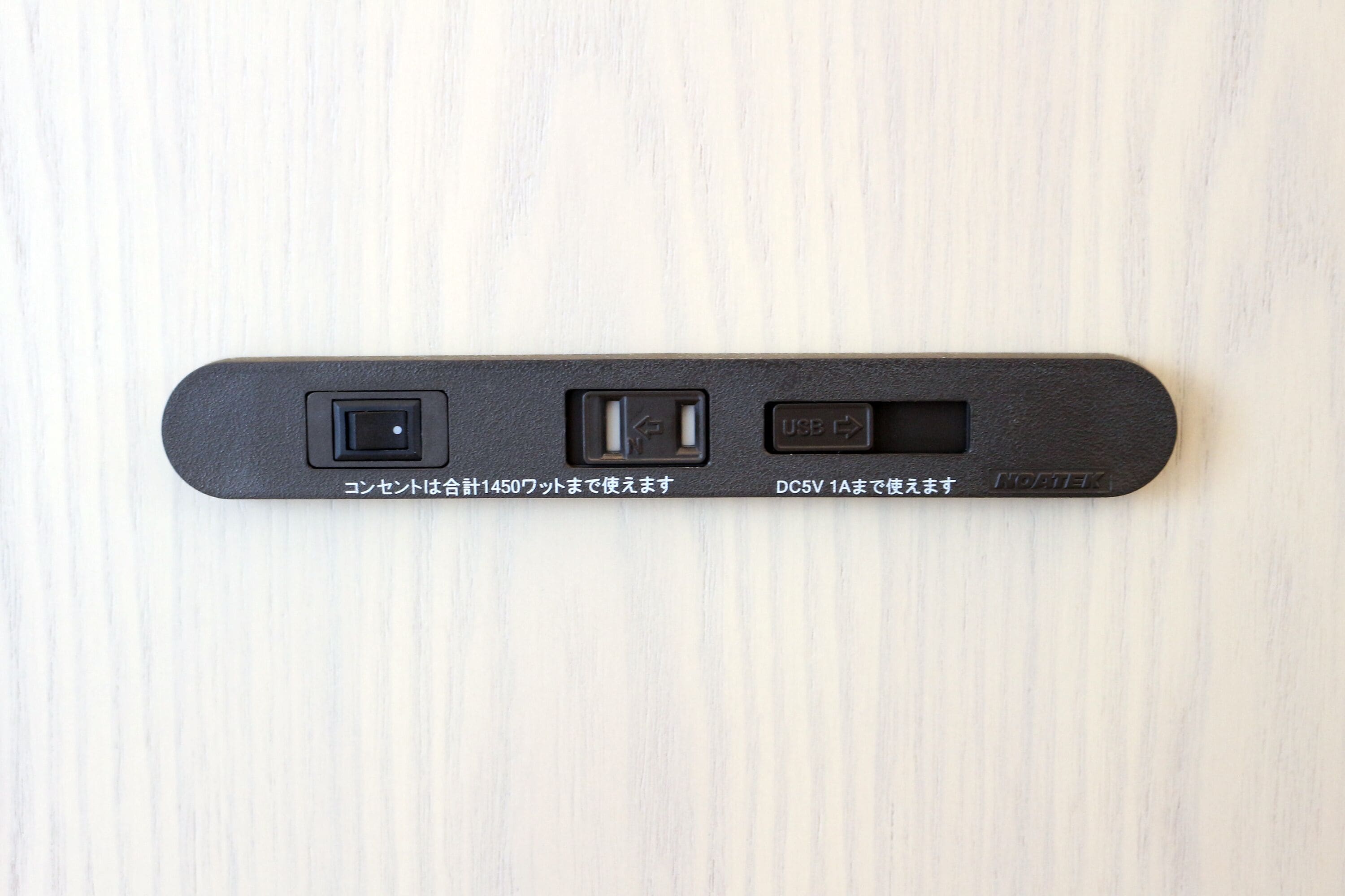 A black device with three ports on a light wooden surface.