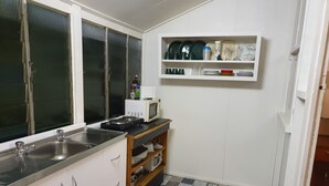 Een kleine keuken met een spoelbak, magnetron en bovenkasten voor servies.