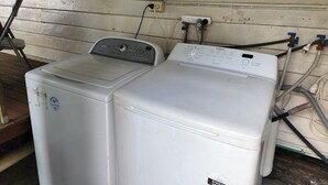 Een was- en droogcombinatie met een bedieningspaneel, aangesloten op een stopcontact en leidingen.