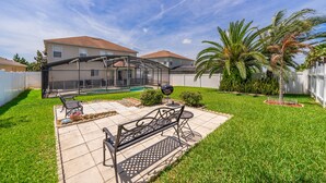 Ein Garten mit überdachter Terrasse, Grill und Pool.