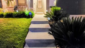 A two-story house with a front entrance, a driveway, and a well-maintained lawn.