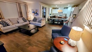 A modern living room with a sofa, coffee table, and a dining area with a table and chairs.