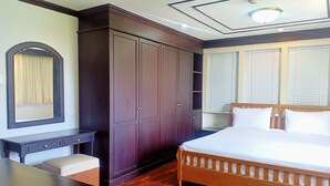 A bedroom with a large wardrobe, a desk, a bed, and a window with blinds. - Supha Maison (Bangkok)
