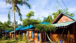 A row of wooden cabins with blue roofs, surrounded by lush greenery and palm trees. - Power Beach Resort (Ko Pha-ngan)