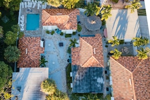 An aerial view of a resort with multiple buildings, a swimming pool, and palm trees.