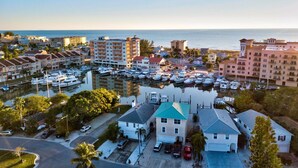 A marina with boats docked, surrounded by residential buildings and a clear view of the ocean.
