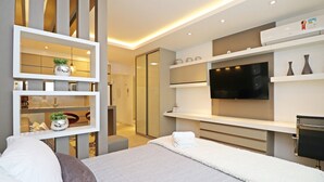 Ein modernes Hotelzimmer mit einem großen Bett, einem Fernseher und integrierten Regalen.