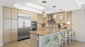 A modern kitchen with a central island, stainless steel appliances, and pendant lighting. - Luxury Resort Spectacular Views of Cascading Pools and Bay; New Lazy River! Boat Slip! (Orange Beach)