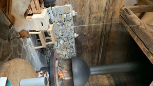 Un rustico camino in pietra con un camino, circondato da travi in legno e un muro in pietra.