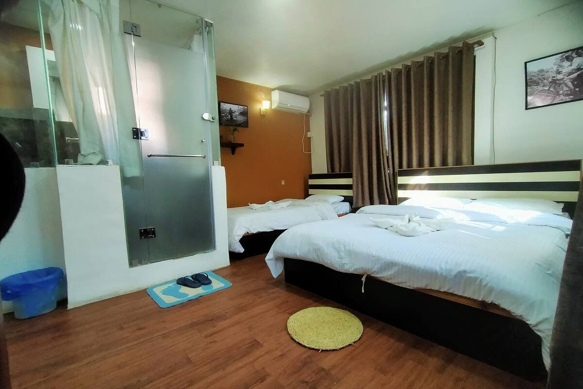 A hotel room with a bed, a shower, a small table, and a wall-mounted TV.