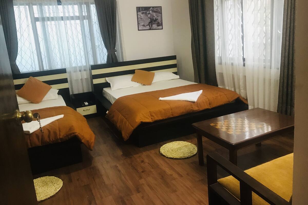 A hotel room with two beds, a small table, and a chair.