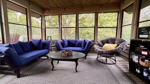 A cozy room with a blue sofa, a round coffee table, and a chair with a yellow pillow.