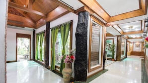A spacious lobby with a polished floor, wooden ceiling beams, and a large vase with flowers. - Piyapruk Resort (Nakhon Ratchasima)