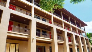 A multi-story hotel with balconies, a covered entrance, and a parking area with motorcycles. - The Room Chaweng (Koh Samui)