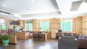A hotel lobby with a reception desk, seating area, and large windows. - The Room Chaweng (Koh Samui)