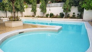 A rectangular swimming pool with a tiled deck area and a curved section. - Modern 6BR House ⭐️City & Ocean Views from Jacuzzi (Cebu City)