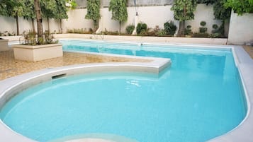 Une piscine rectangulaire dotée d’une plage carrelée et d’une partie incurvée.