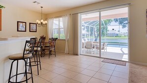 Eine geräumige Küche mit Essbereich, großen Schiebeglastüren zum Pool und einem Deckenventilator.