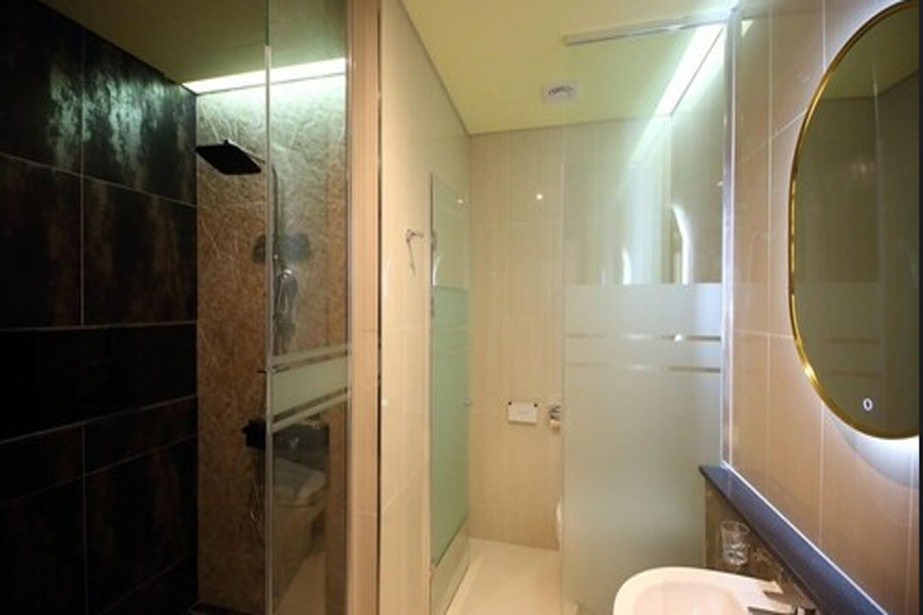 A modern bathroom with a glass-enclosed shower, a toilet, and a sink.