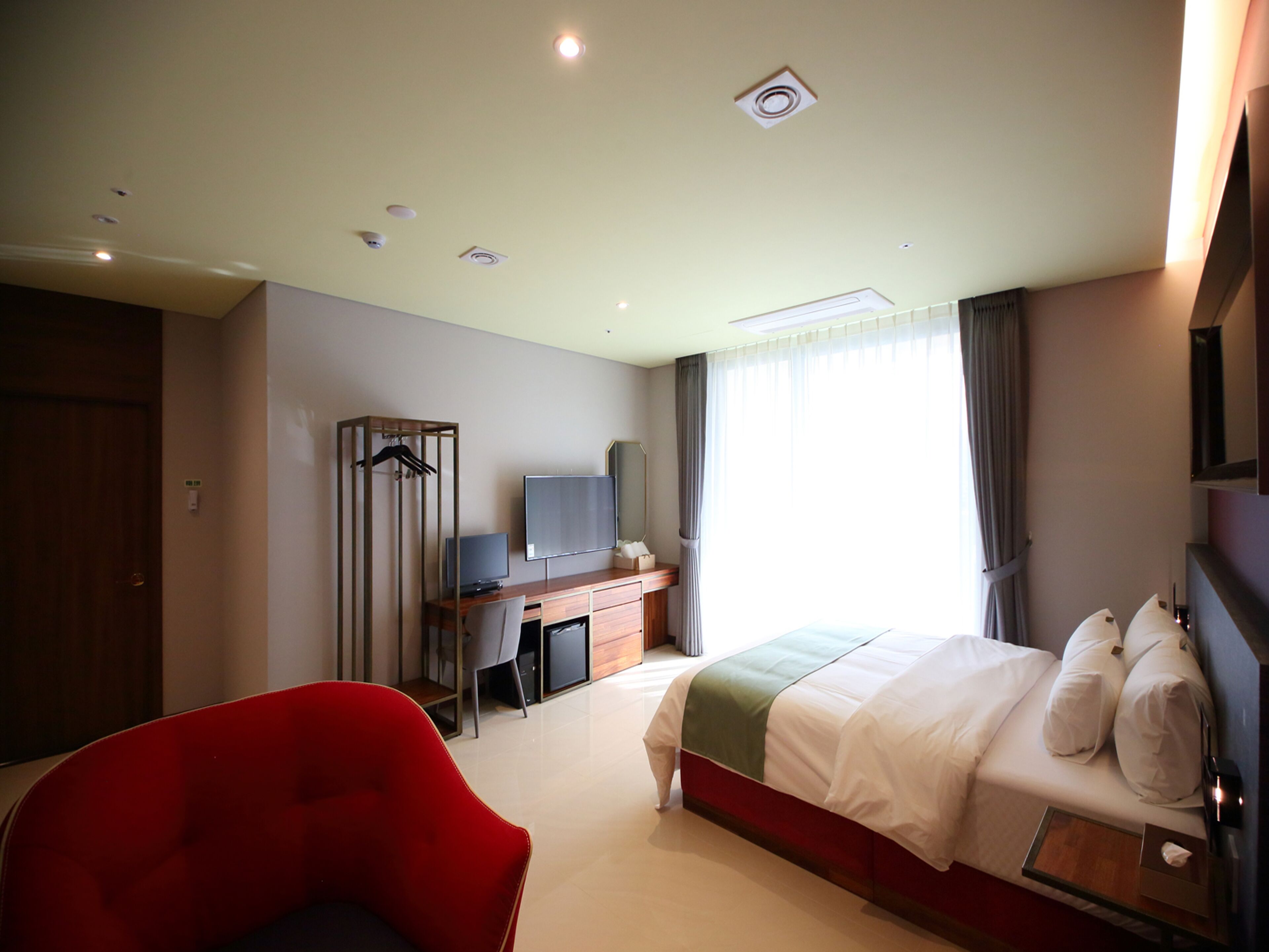 Une chambre d’hôtel moderne équipée d’un lit, d’un bureau, d’une chaise, d’une télévision et d’une armoire.