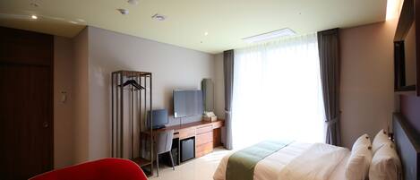 Une chambre d’hôtel moderne équipée d’un lit, d’un bureau, d’une chaise, d’une télévision et d’une armoire.