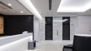 A modern reception area with a reception desk, two elevators, and a seating area.