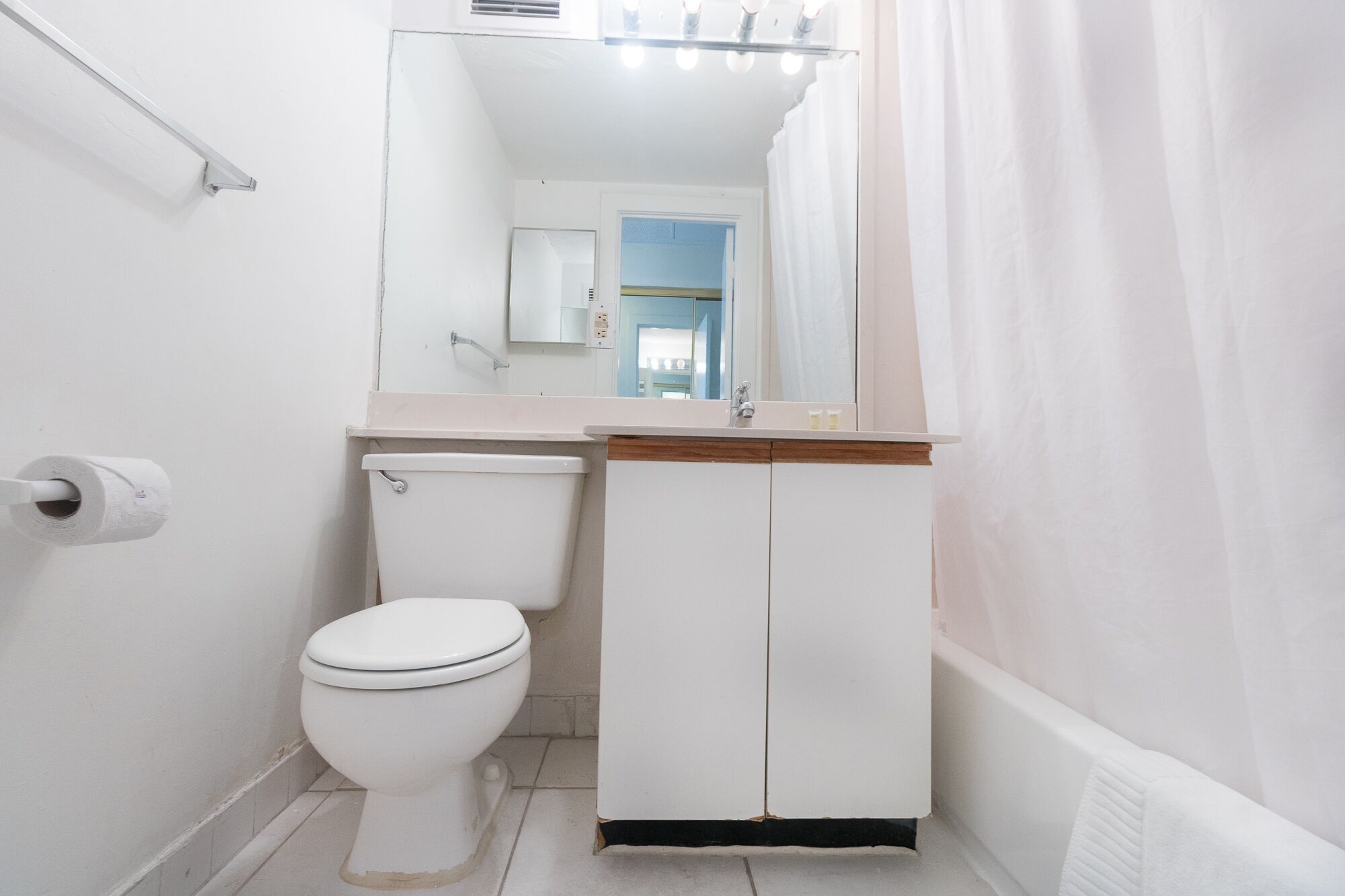 A small, white bathroom with a toilet, a sink, and a mirror above it.