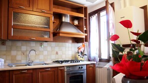 A kitchen with wooden cabinets, a stainless steel stove, and a tiled backsplash. - Moira's House (Venezia)