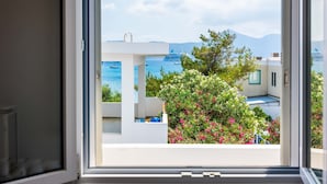 A balcony with a view of the sea, a ship, and distant mountains. - White Rock Milos Suites (Milos)
