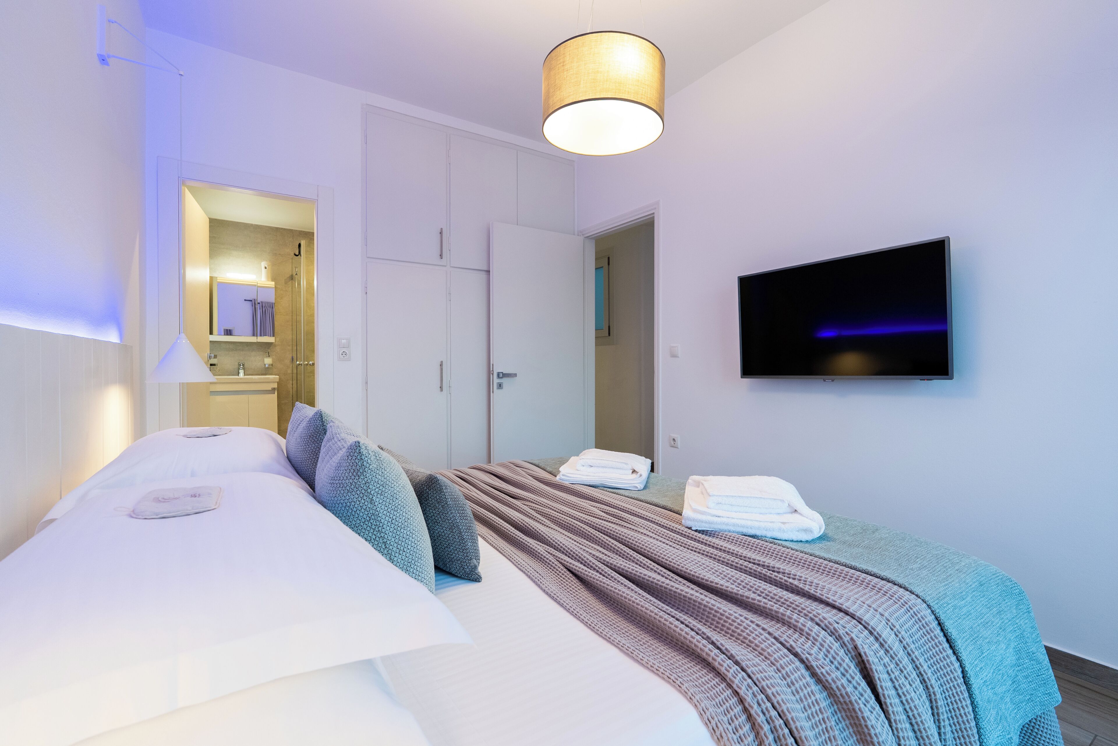 Une chambre d’hôtel avec un lit, une télévision, une armoire et un miroir.