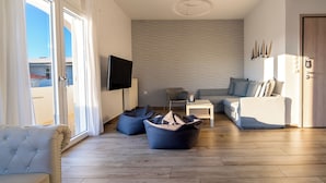 A modern living room with a sofa, a coffee table, and bean bags. - White Rock Milos Suites (Milos)