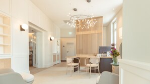 A modern reception area with a wooden reception desk, two white chairs, and a decorative light fixture.