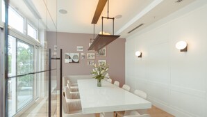A modern dining area with a white table, white chairs, and a vase of flowers.