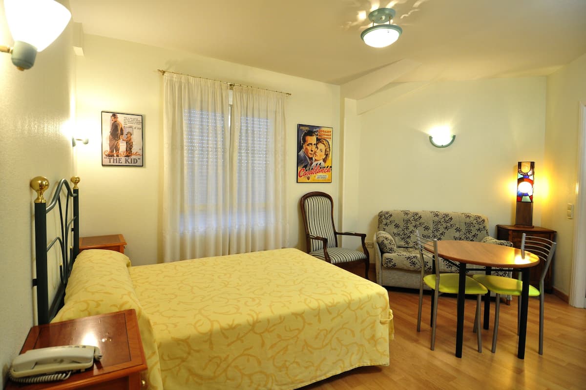 Ein Hotelzimmer mit einem Bett, einem kleinen Tisch, zwei Stühlen, einem Sofa und einer Wandlampe.