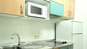 Une cuisine avec des meubles en bois, un évier en acier inoxydable, un four à micro-ondes et un réfrigérateur blanc.