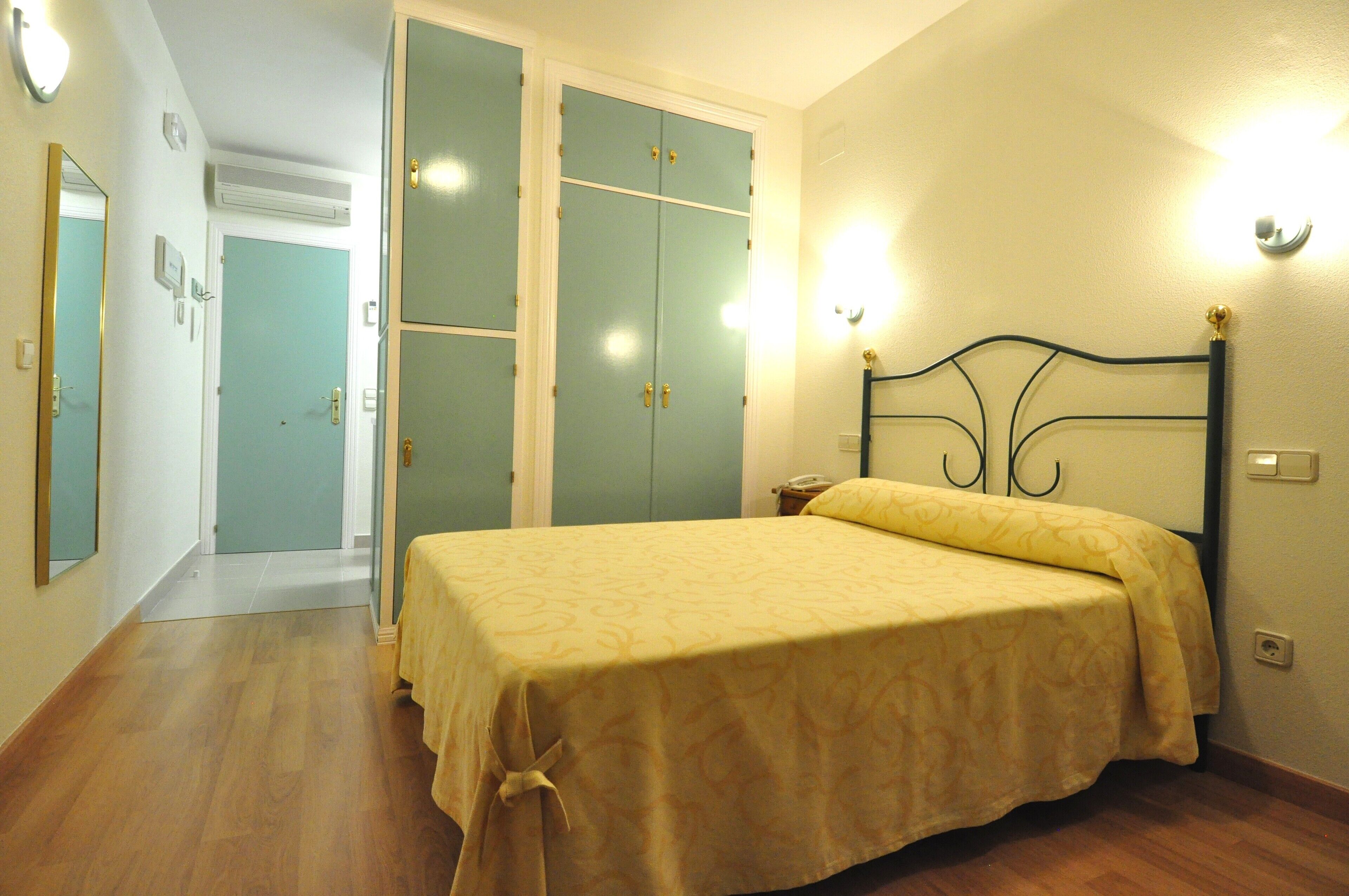 Un dormitorio con cama, armario y mesita de noche.